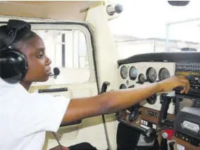  ?? ?? A female student of the Aeronautic­al School of the West Indies in the cockpit of an aircraft during flight training.