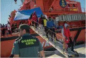  ?? — AFP ?? Migrants rescued at sea disembark from a boat as they wait to be transferre­d at the harbour of Algeciras.