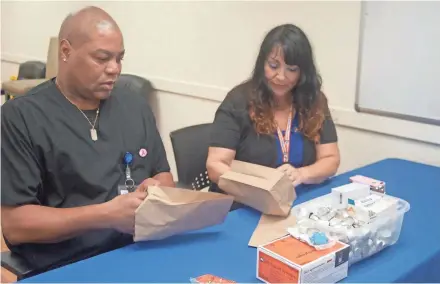  ?? EDGAR MENDEZ / FOR THE JOURNAL SENTINEL ?? Gina Allende, health promotions manager at UMOS, and outreach worker Naronne Cole Sr. package syringes, cookers, alcohol pads and cotton pellets for clients of the UMOS Safe Exchange Program on Milwaukee's south side.