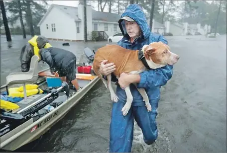  ?? Chip Somodevill­a Getty Images ?? VOLUNTEERS from around North Carolina help rescue residents and pets from f looded homes on Friday in hard-hit New Bern, N.C.