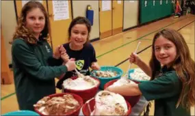  ?? BILL RETTEW JR. – DIGITAL FIRST MEDIA ?? Chesterbro­ok Academy Elementary School fifth-graders, Sam Ehrich, left, Hope Knoebel and Madeline Cunningham stir ice cream prior to turning their teachers and principal into human sundaes.