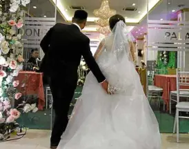  ?? —AFP ?? Huong (right) and Quan enter the wedding hall in Hanoi to get ‘married.’