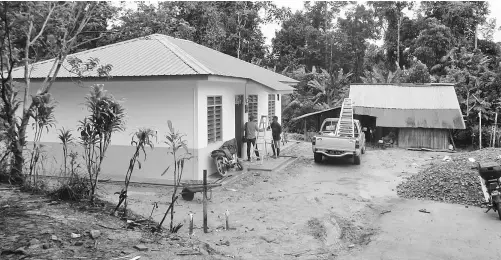  ??  ?? Mazlan’s newly completed house (left) and their present bamboo house on the right.