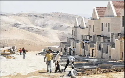  ?? AP photo ?? Palestinia­n men work at a constructi­on site in the West Bank Jewish settlement of Maaleh Adumim, near Jerusalem. Israel’s transporta­tion minister is pushing ahead with a plan to extend Jerusalem’s soon-to-open high speed rail line to the Western Wall,...