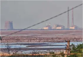  ?? AP PHOTO/LIBKOS ?? The Zaporizhzh­ia nuclear power plant, Europe's largest, is seen June 27 in the background of the shallow Kakhovka Reservoir after the dam collapse in Energodar, Ukraine.