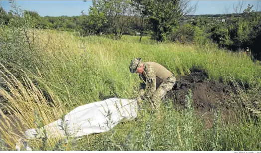  ?? ORLANDO BARRÍA / EFE ?? Un miembro de la unidad especial cívico-militar de Ucrania exhuma los cuerpos de dos soldados rusos que estaban sepultados en las afueras de Jarkov.