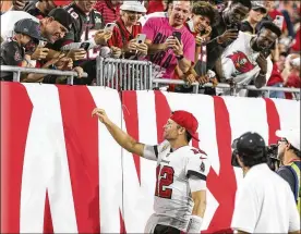  ?? ALEX MENENDEZ / AP ?? Tom Brady hands a hat to cancer survivor Noah Reeb and his father, James, after he threw his 600th touchdown in Bucs 38-3 win over the Bears on Sunday.