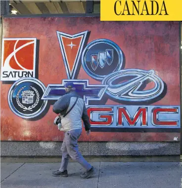  ?? COLE BURSTON/BLOOMBERG ?? A pedestrian walks past a mural depicting vehicle brands in downtown Oshawa. After churning out cars and trucks for more than a century, Oshawa was stunned by the news of General Motors’ planned pullout on Monday.