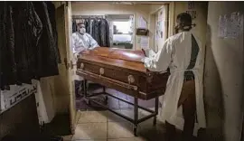  ?? Robert Gauthier Los Angeles Times ?? ATTENDANTS at Continenta­l Funeral Home in Los Angeles move a casket. The funeral home has been overwhelme­d in the past year by the COVID-19 pandemic.