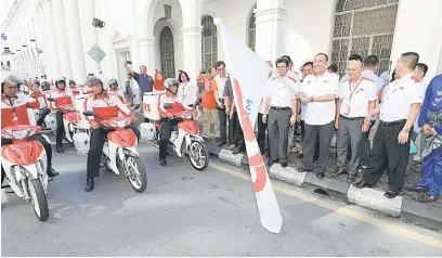  ?? — Gambar Chimon Upon ?? SIMBOLIK: Jailani (tiga kanan) melepaskan unit posmen pos serahan, posmen pos laju dan pos bergerak sebagai simbolik sambutan Hari Pos Sedunia 2017 di Kuching semalam.