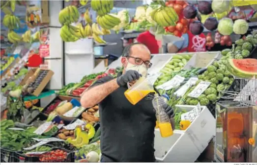  ?? JUAN CARLOS MUÑOZ ?? Un trabajador llena una botella zon zumo de naranja en un puesto de frutas, ayer en Sevilla.