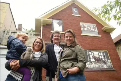  ?? DAVID BEBEE, RECORD STAFF ?? From left, Maggie Laurin with daughter Eleanor, 3, John Cunningham and Laura McBride, in front of their artwork on a vacant home in Central Frederick. With profession­al artist McBride leading the way neighbours pulled together to make the buildings...