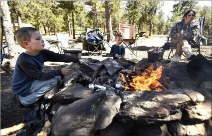  ?? JEREMY PAPASSO, THE DAILY CAMERA ?? Davion Nickens, 6, at left, and his brother Wyatt, 4, cook hot dogs on the campfire with their mother Anna, at right, in an area of National Forest near Gordon Gulch near the town of Nederland.