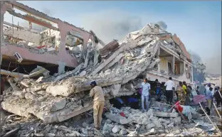  ?? Associated Press photo ?? Somalis gather and search for survivors by destroyed buildings at the scene of a blast in the capital Mogadishu, Somalia on the weekend.