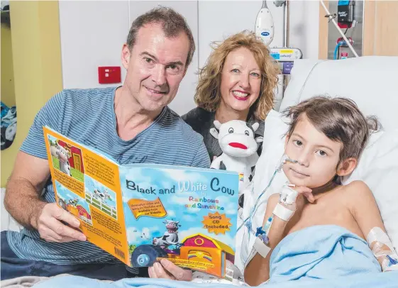  ?? Picture: JERAD WILLIAMS ?? Roger Sharpe reads son James Sharpe, 6, a book provided by charity, Rainbows and Sunshine, with founder Lyn Rourke.