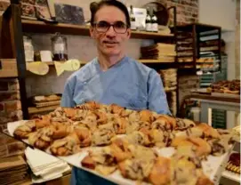  ?? THOMAS SAMSON/AFP VIA GETTY IMAGES ?? French pastry chef Stéphane Louvard with his crookies, traditiona­l French croissants mixed with cookie dough, in his pastry shop in Paris.