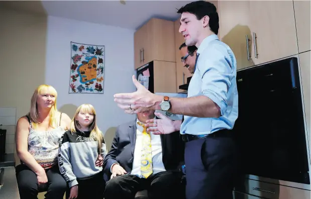  ?? JEFF MCINTOSH / THE CANADIAN PRESS ?? Prime Minister Justin Trudeau speaks with Tracey Hume and her granddaugh­ter Desiree Hume, 11, in their apartment in Calgary on Thursday.