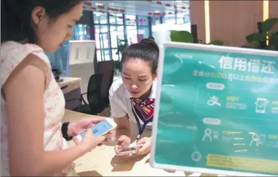  ?? XU KANGPING / FOR CHINA DAILY ?? A customer uses Zhima Credit, a credit-scoring mechanism of Ant Financial Services Group, with her mobile phone in Hangzhou, capital of Zhejiang province.