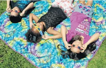  ?? TAIMY ALVAREZ/STAFF PHOTOGRAPH­ER ?? Raylan Letourneau, 6, left, Zoe Holladay, 6, and Orion Letourneau, 9, of Weston stay comfortabl­e as they experience the eclipse at the Fox Observator­y at Markham Park.