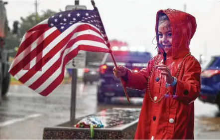  ?? Michael Ciaglo photos / Houston Chronicle ?? Ariana Mendoza, 5, waves an American flag while watching the Lindale Fourth of July Parade on Wednesday. Below, the Houston Highlander­s Pipes and Drums perform, even as a flash flood warning was declared.