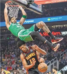  ?? BRYNN ANDERSON AP ?? Celtics forward Jayson Tatum, who had 30 points, scores against the Hawks’ DeAndre Carter during the first half of Game 6. Boston eliminated Atlanta 4-2.