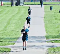  ??  ?? Joggers keep their distance on Clapham Common in south London yesterday