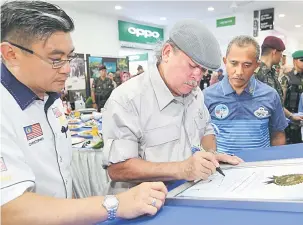  ?? — Gambar Bernama ?? SELESAI: Sultan Ibrahim (tengah) menandatan­gani Sijil Malaysia Book of Record ‘Struktur Batu Karang Tiruan Terbesar’ di Mersing Harbour Center, semalam.