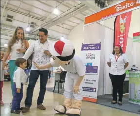  ??  ?? Una familia recibe el saludo de la botarga de Grupo Boxito en el escaparate de esa empresa en la Expo Feria del Comercio, que celebra su edición número 20 y que conmemoró con el tradiciona­l pastel y las piñatas