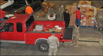  ?? Staff photo/ Alex Guerrero ?? Members of the Ohio National Guard load food into the bed of a pickup truck during a food distributi­on at the Auglaize County garage last week.