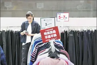  ??  ?? In this file photo, an employee browses her smartphone at a clothing store having a promotion sale at a shopping mall in Shenzhen, China’s Guangdong province. China has raised its estimate of the size of its economy by 2.1% following a census, raising its gross domestic product for 2018 to 91.93 trillion yuan ($13.1 trillion), the National
Bureau of Statistics said, Nov 22. (AP)