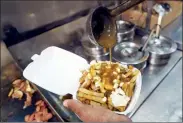  ?? CANADIAN PRESS FILE PHOTO ?? A cook prepares poutine at La Banquise restaurant in Montreal.