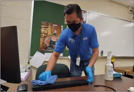  ?? DAVID ANGELL — FOR THE MACOMB DAILY ?? Rolando Delos Santos, a custodian in the Utica Community Schools, cleans a keyboard after school at Bemis Junior High in Sterling Heights. Cleaning standards, with a focus on touch points, has increased at public schools during the COVID-19 pandemic.