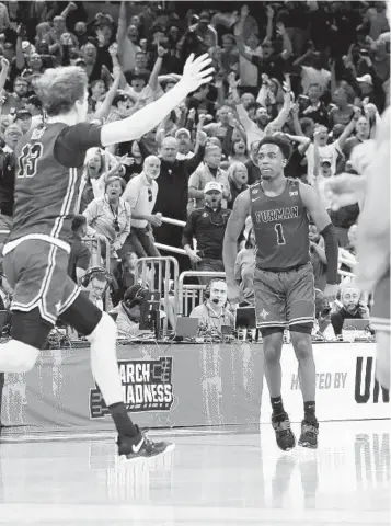  ?? K.C. ALFRED U-T ?? Furman’s J.P. Pegues (1) reacts after hitting the winning 3-point basket to beat the Virginia Cavaliers in the first round. The Paladins were down by two, but Garrett Hein (left) intercepte­d a pass and fed Pegues.