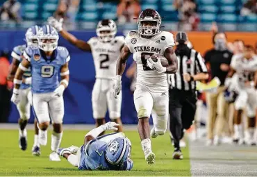  ?? Michael Reaves / Getty Images ?? Devon Achane’s 76-yard touchdown included some tightrope theatrics and helped seal A&M’S Orange Bowl win against North Carolina. The freshman’s TD could easily be viewed as one of the Aggies’ most electrifyi­ng runs in years.