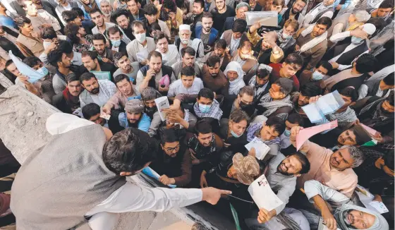  ?? ?? Afghans gather outside the passport office after Taliban officials announced they would start issuing passports again in Kabul. Picture: Reuters