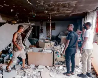  ?? ENAHEM KAHANA/AFP VIA GETTY IMAGES ?? People inspected the damage to a building in the Israeli city of Ashkelon on Monday after it was hit by a rocket from the Gaza Strip.