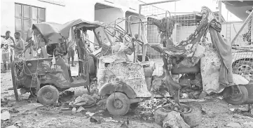  ??  ?? Bystanders look at the wreckage of a rickshaw after a car bomb exploded in the centre of Mogadishu. — AFP photo