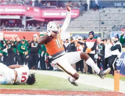  ?? MIKE STOBE/GETTY ?? Hurricanes quarterbac­k Jacurri Brown slides for a touchdown in UM’s loss to Rutgers in the Pinstripe Bowl at Yankee Stadium on Dec. 28.