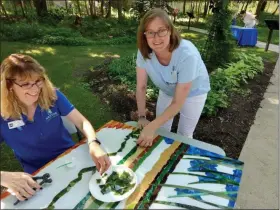  ?? SUBMITTED ?? Mentor Public Library Reference Director Amy Senning and Executive Director Cheryl Kuonen piece together a glass mural of Mentor Marsh that will adorn Mentor Public Library’s Main Branch.