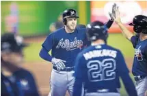  ?? BRYNN ANDERSON/AP ?? Atlanta’s Freddie Freeman high fives his teammates after launching a two-run home run in the first inning against Miami starter Jose Urena.