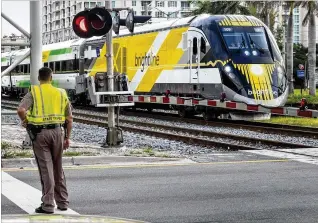  ?? LANNIS WATERS / THE PALM BEACH POST ?? In July, off-duty officers were stationed at Florida East Coast Railway crossings in downtown West Palm Beach as Brightline upgraded the tracks’ signal system. On Tuesday, the company announced that the fifth and final train need to run the first leg...