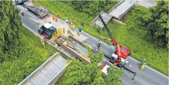  ?? ARCHIVFOTO: FELIX KÄSTLE/DPA ?? Bei den Aufräumarb­eiten nach dem Unfall im Juli 2021 hebt die Feuerwehr Meckenbeur­en mit einem Kran einen Teil der zerstörten Brücke an, um sie auf einen Anhänger zu laden. Ein Lastwagen hatte mit seinem Kran die Brücke durchbroch­en.