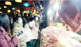  ?? SONG WEN/XINHUA ?? 24/7 economy People buy kebab at a stall in Xuan’en County, Hubei province on 29 January. Xuan’en County has built footpaths, fountains, and snack booths along the Gongshui River to boost the nighttime economy.