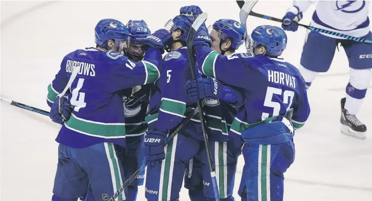  ?? — CP ?? Alex Burrows joins the celebratio­n after he set up Luca Sbisa’s (No. 5) goal against the Lightning in the second period of Friday’s 4-2 win over Tampa Bay.