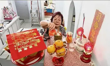  ??  ?? Sweet offerings: Sim praying and making offerings to the Kitchen God at her home in Lengkok P. Ramlee, Penang.