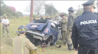  ??  ?? Bomberos voluntario­s trabajan para rescatar el cuerpo del uniformado, que quedó atrapado en el habitáculo del automóvil durante varias horas.