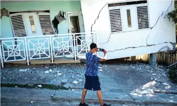  ?? — AFP photo ?? A man takes photos of a house damaged by a 5.8 earthquake in Guanica, Puerto Rico.