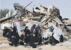  ??  ?? 0 Bedouin women sit in front of the demolished building