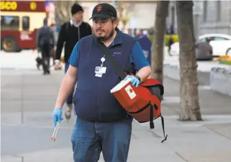  ?? Paul Chinn / The Chronicle ?? Jose Luis Guzman of the Department of Public Health collects syringes near the Civic Center.