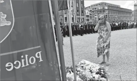  ?? GEERT VANDEN WIJNGAERT/AP PHOTO ?? A woman cries as she walks by police officers during a moment of silence for shooting victims near the City Hall in Liege, Belgium, on Wednesday. A gunman killed three people, including two police officers, in the Belgian city of Liege on Tuesday....